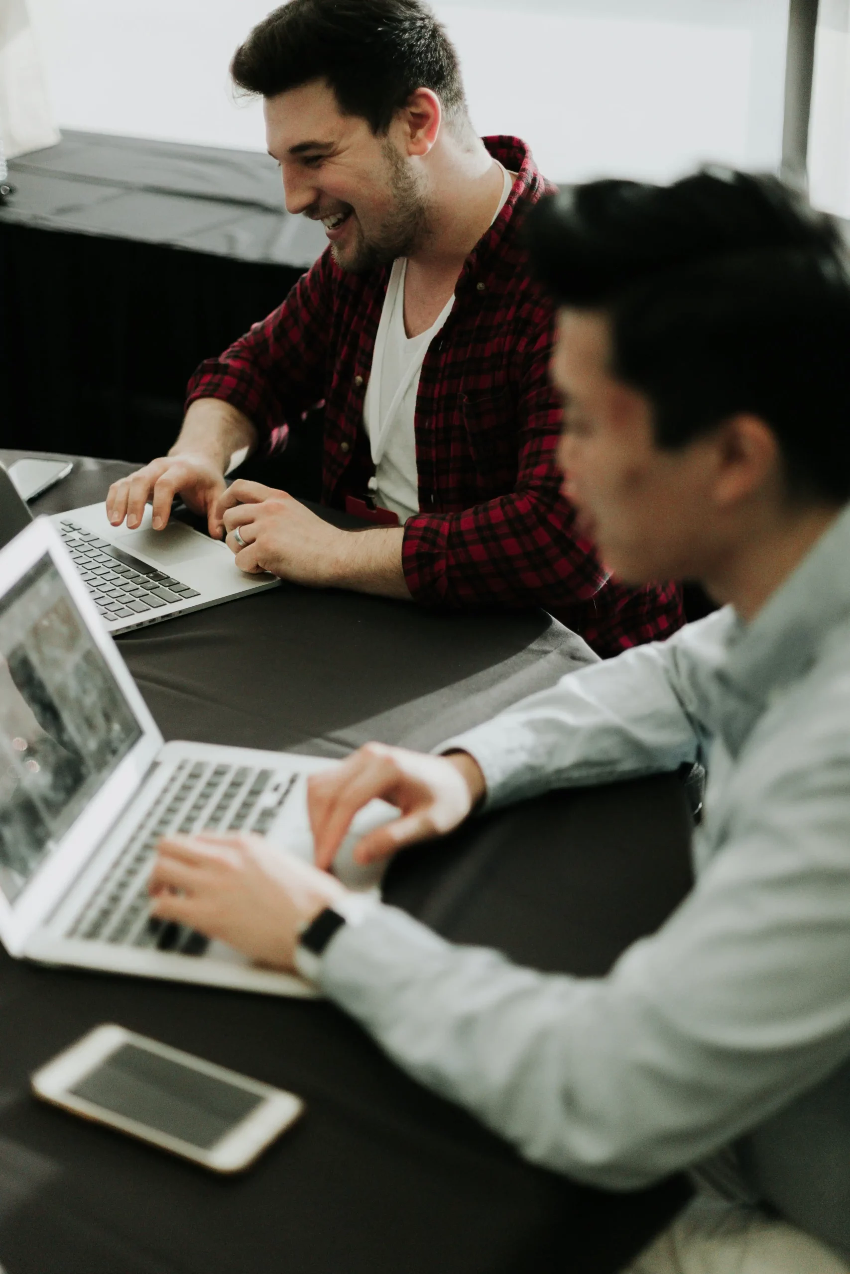 Deux collaborateurs travaillant ensemble sur leurs ordinateurs portables lors d'une session de travail